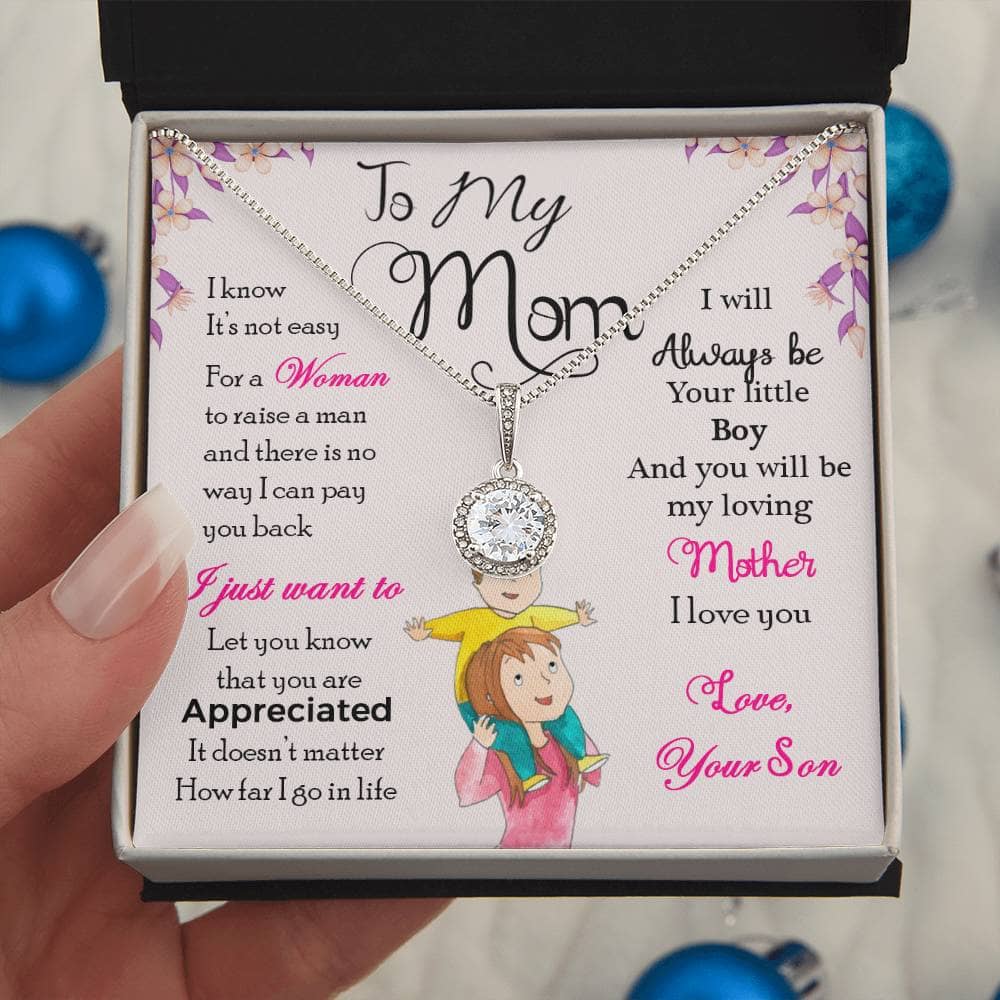 Alt text: "A hand holding a personalized Mother's Day necklace in a box, symbolizing the unyielding bond between mothers and their children."