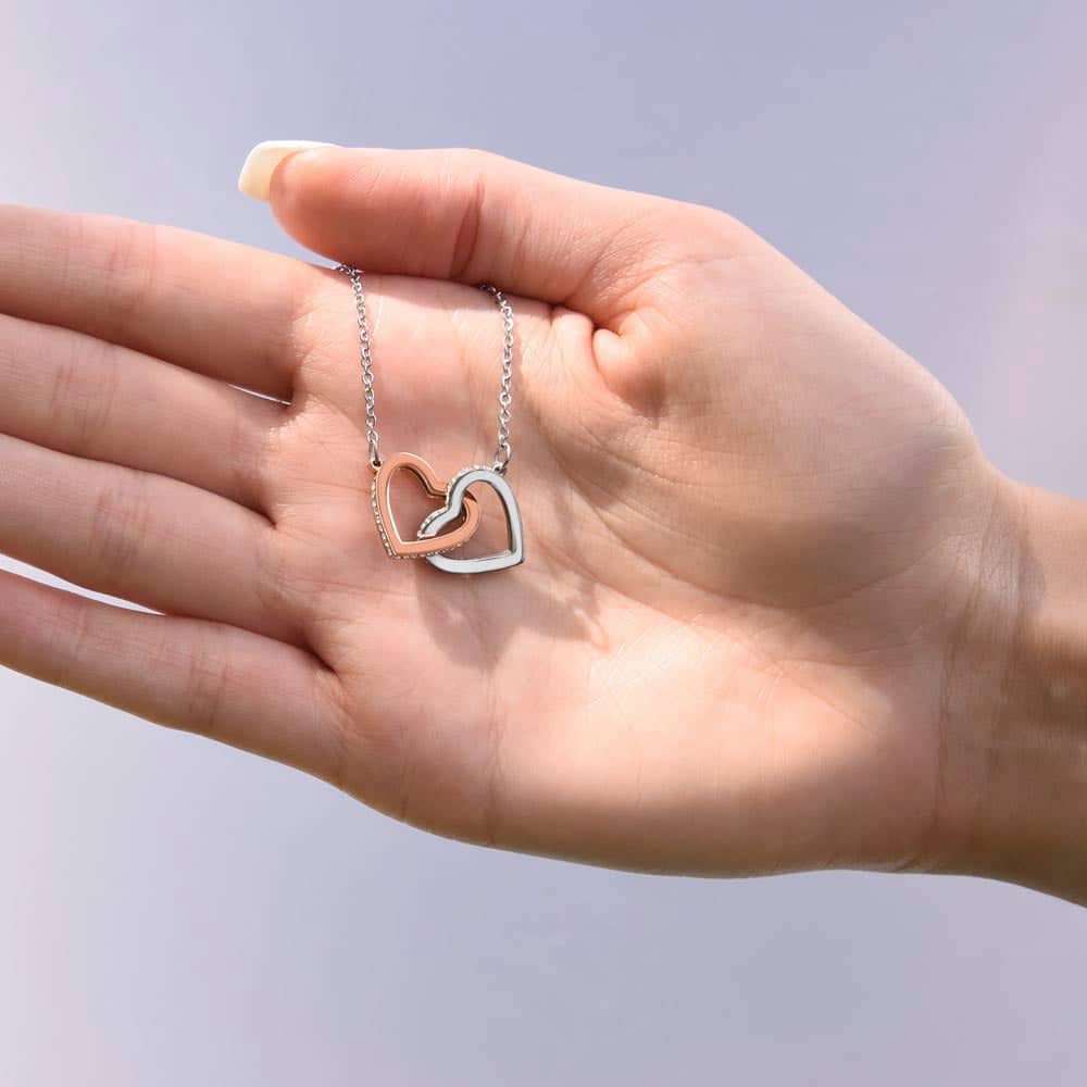 Alt text: "A hand holding the Beloved Soulmate Interlocking Hearts Necklace - Forever & Always, a symbol of enduring love and devotion. Made with 14k white gold and cubic zirconia, it's a personalized piece that celebrates the unbreakable bond between soulmates."