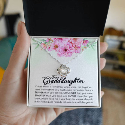 Alt text: "A hand holding a personalized granddaughter necklace in a box, featuring a heart-shaped pendant with a halo of cubic zirconia."
