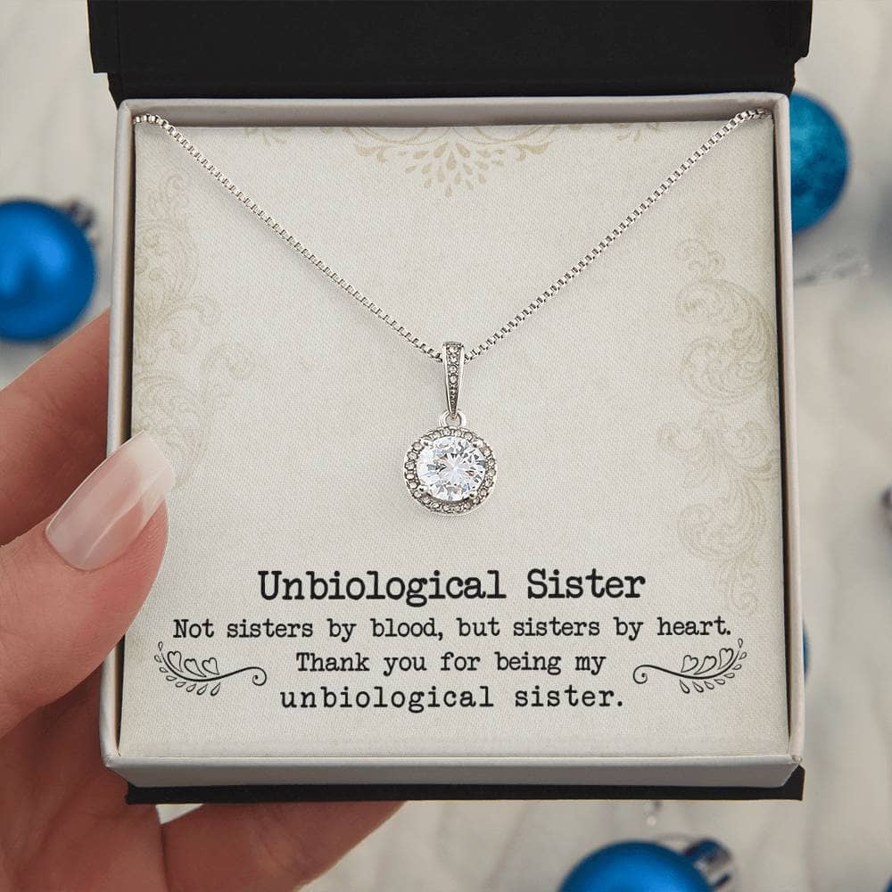 Alt text: "A hand holding a Personalized Unbiological Sisters Necklace in a box"