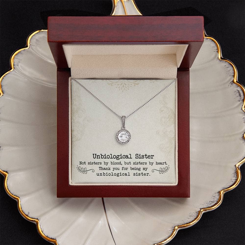 Alt text: "Personalized Unbiological Sisters Necklace in a box on a plate"