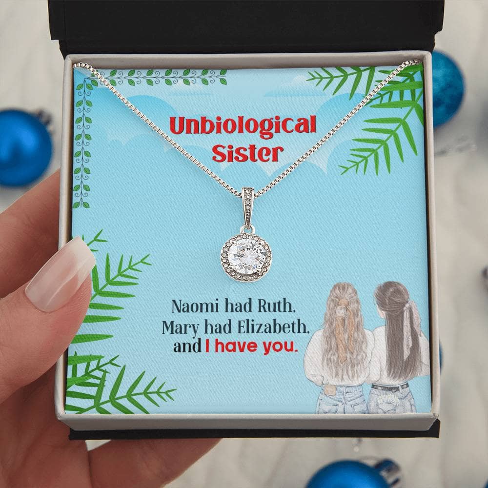 A hand holding a Custom Unbiological Sisters Eternal Hope Necklace in a box, symbolizing an unbreakable bond between sisters.