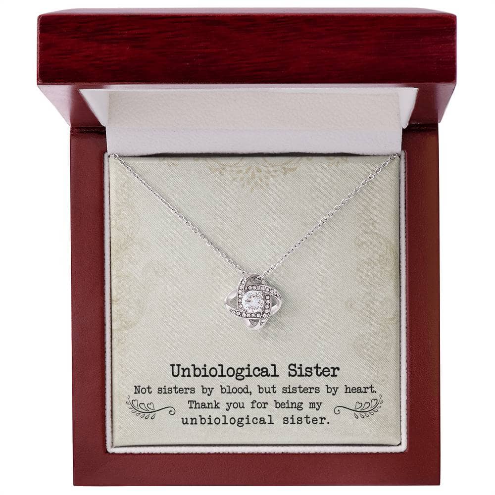A close-up of the Custom Unbiological Sisters Love Knot Necklace, a necklace in a box with interlocking hearts or love knot designs.