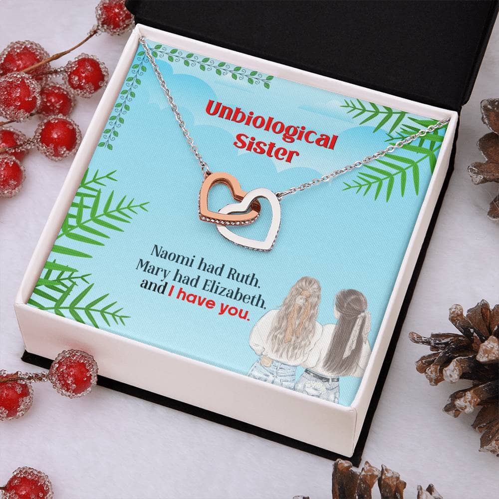 Alt text: "Custom Unbiological Sisters Necklace with Interlocking Hearts in a box with book and berries"