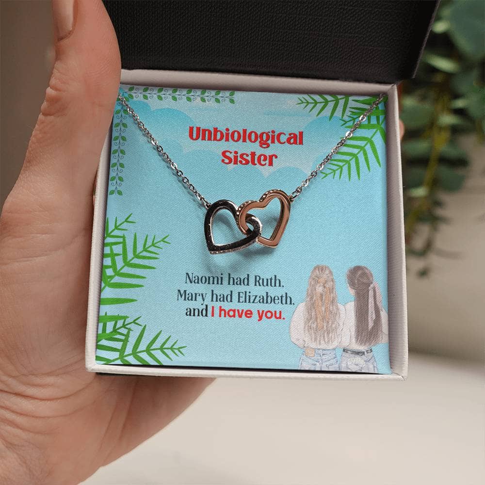 A hand holding a Custom Unbiological Sisters Necklace with Interlocking Hearts, symbolizing the unbreakable bond between sisters.