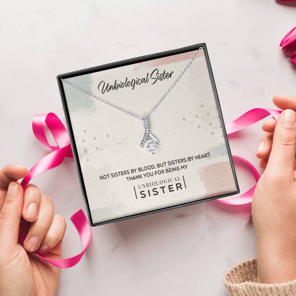 A person holding a Customizable Unbiological Sisters Love Knot Necklace, a symbol of sisterhood, love, and cherished moments.