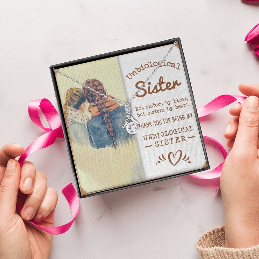 Alt text: "Hands holding a box with a picture of a girl and pink ribbon, showcasing the Customized Unbiological Sisters Alluring Charm Necklace."