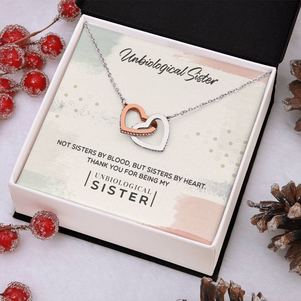 Alt text: "Customized Unbiological Sisters Heart-Link Necklace in box with pine cones and berries"