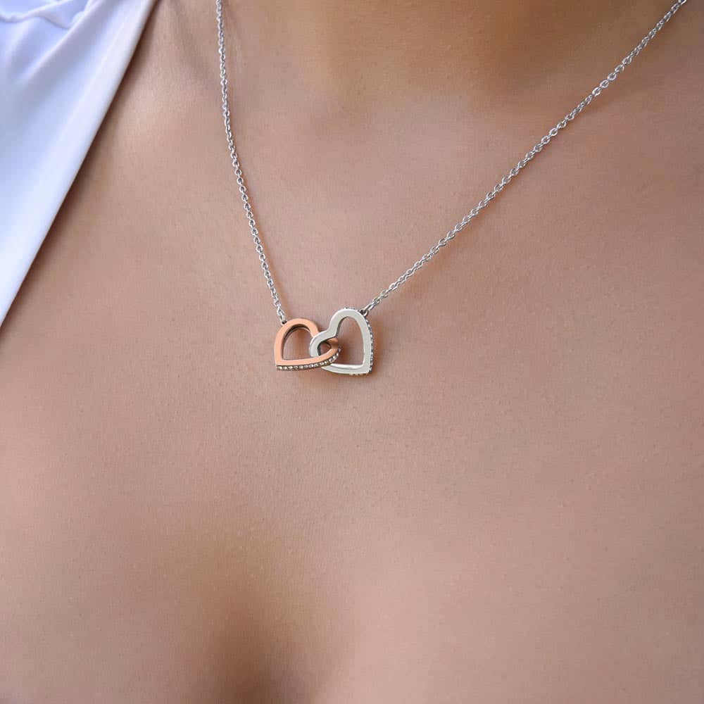 A close-up image of a Customized Unbiological Sisters Heart-Link Necklace, featuring a pendant with interlocking hearts or a love knot design. Crafted with 14k white gold or 18k gold finish, adorned with cushion-cut cubic zirconia. Adjustable chain options include a cable chain or a box chain. Packaged in a luxurious mahogany-style box with LED lighting. A symbol of the unbreakable bond between unbiological sisters.