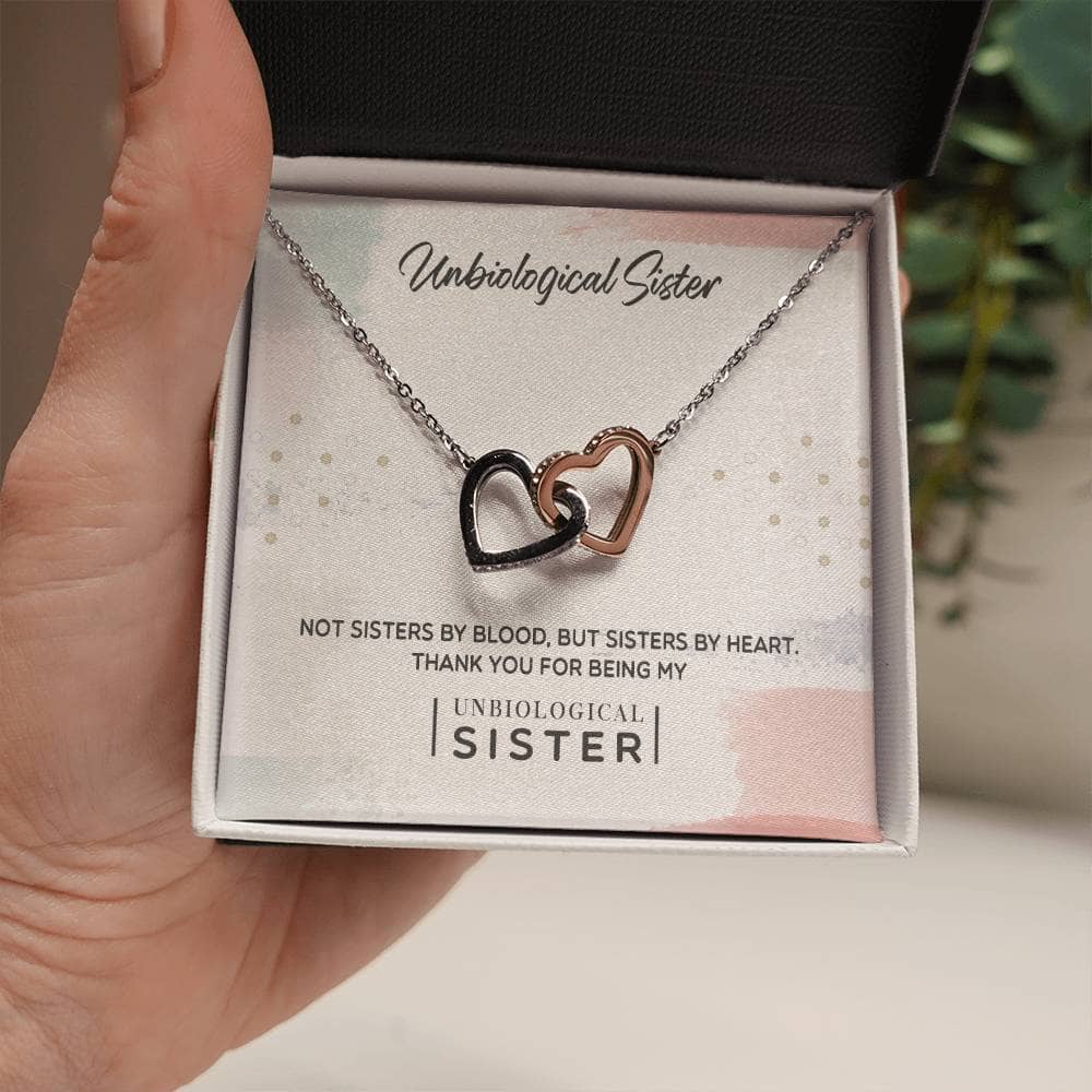 A hand holding a Customized Unbiological Sisters Heart-Link Necklace, symbolizing the powerful bond between sisters of spirit. Crafted with 14k white gold or 18k gold finish, adorned with glimmering cubic zirconia.