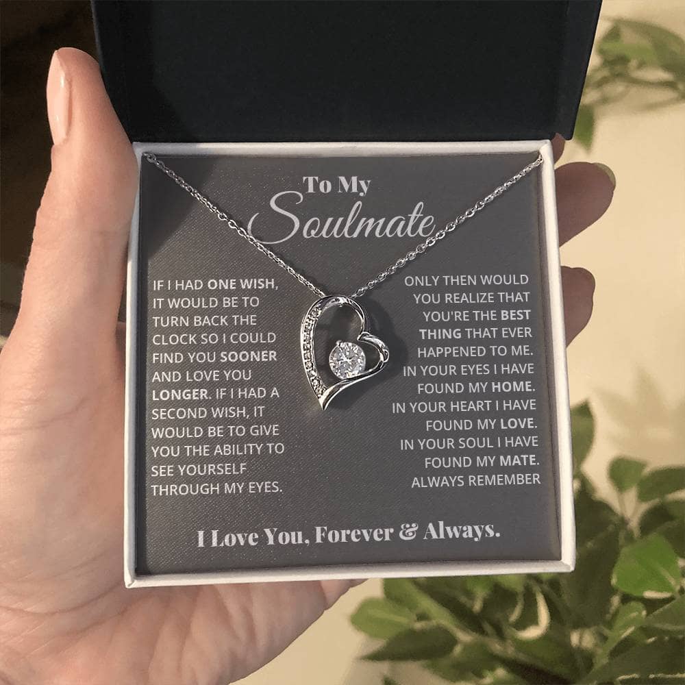 A hand holding the Eternal Love Necklace in a box, featuring a heart pendant with a sparkling 6.5mm CZ crystal centerpiece.