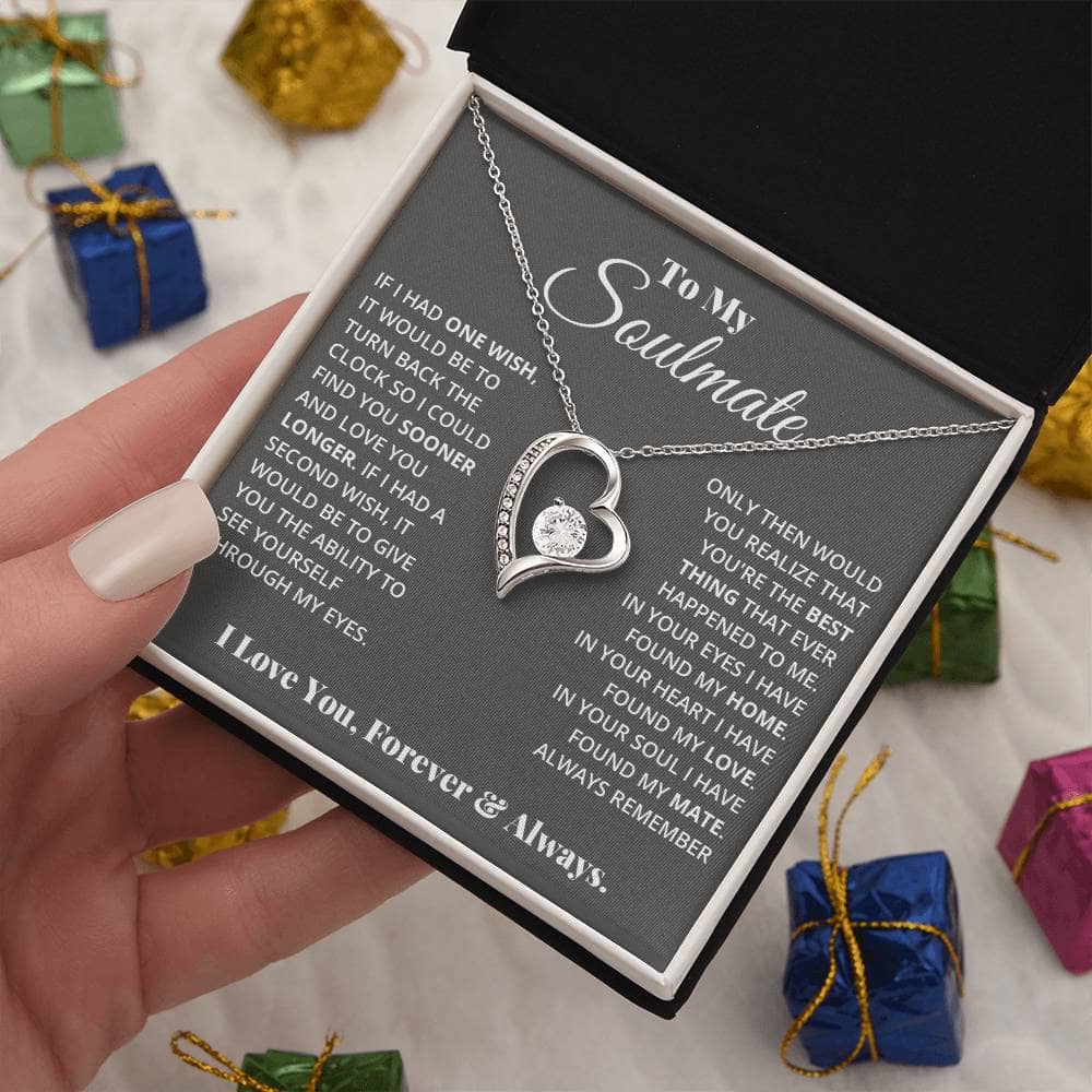 Alt text: "A hand holding the Eternal Love Necklace in a box, a heart-shaped pendant with a sparkling 6.5mm CZ crystal centerpiece, adorned with tiny crystals."