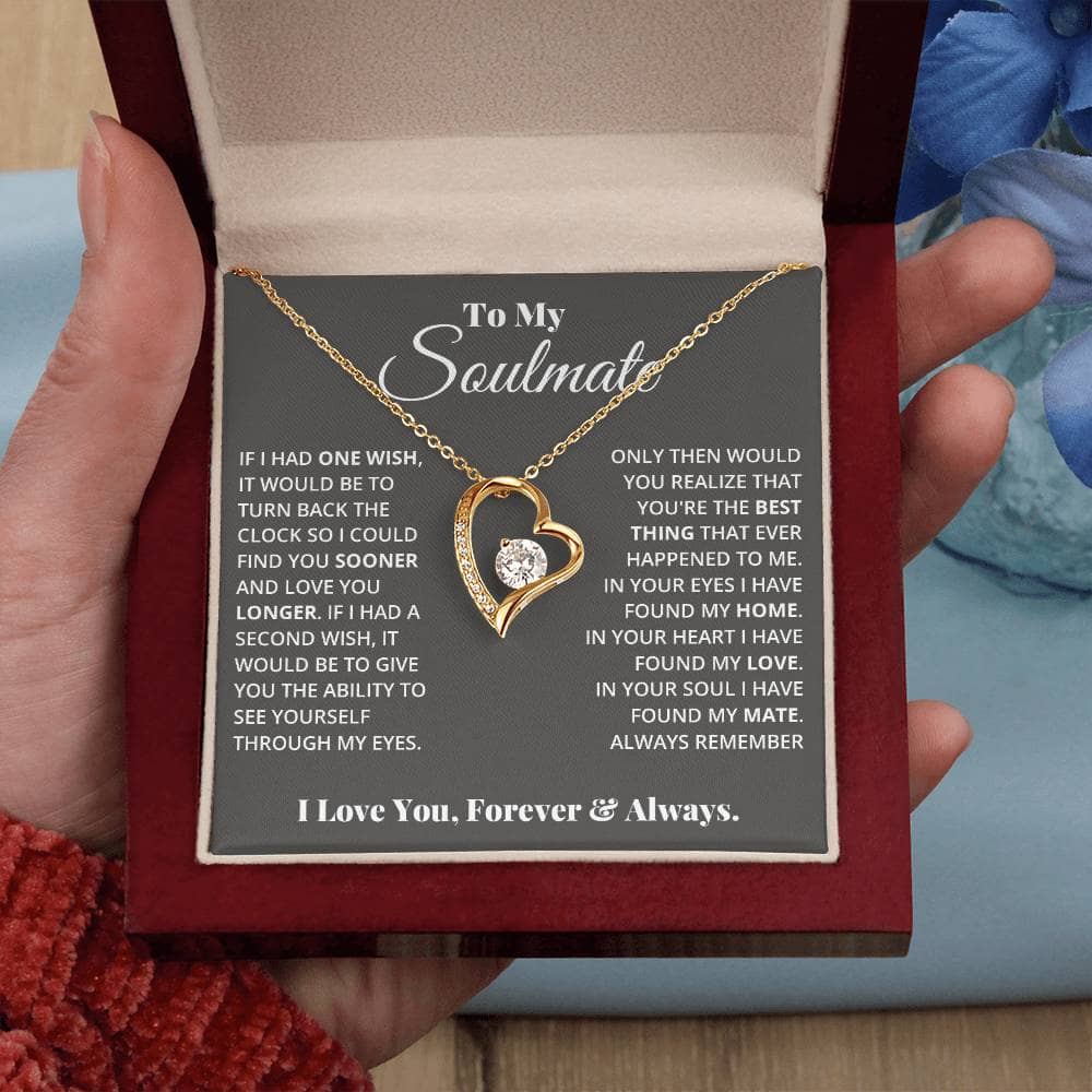 Alt text: "Hand holding Forever Love Necklace in box, heart pendant with CZ crystal, adorned with tiny crystals, customizable and adjustable chain length, secure lobster clasp attachment."