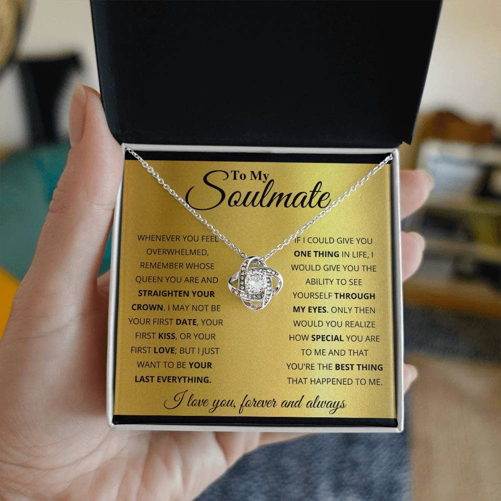 A hand holding a "From Me to My Soulmate" Unique Love Knot Necklace in a box.