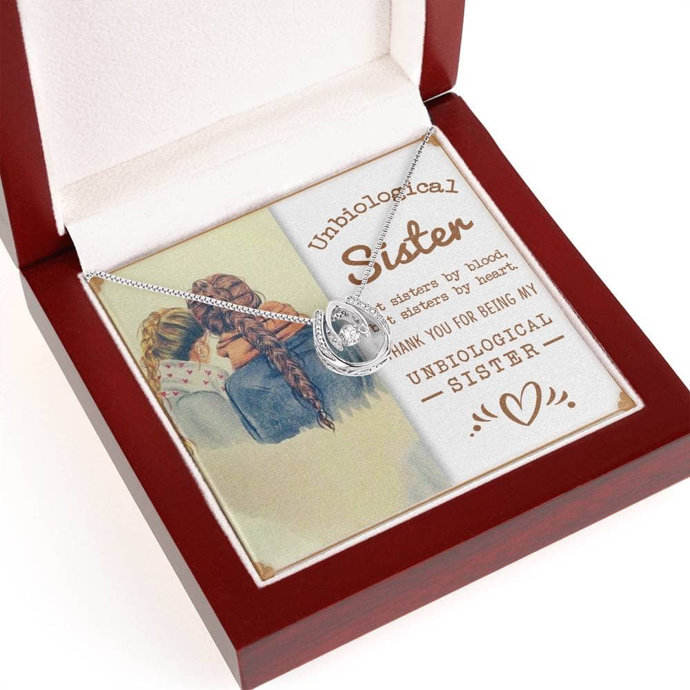 Alt text: "Heartfelt Unbiological Sisters Necklace in a box, adorned with cubic zirconia. Crafted with love, symbolizing an unbreakable bond. 14k white gold or 18k gold finish. Adjustable cable or box chain. Artfully packaged in a mahogany-style box with LED lighting. Ideal gift for special occasions."