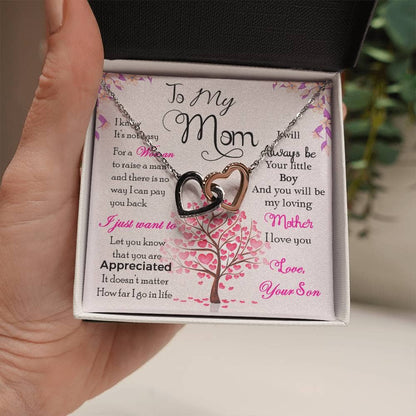 A hand holding a personalized mother necklace in a mahogany-style gift box with LED lighting.