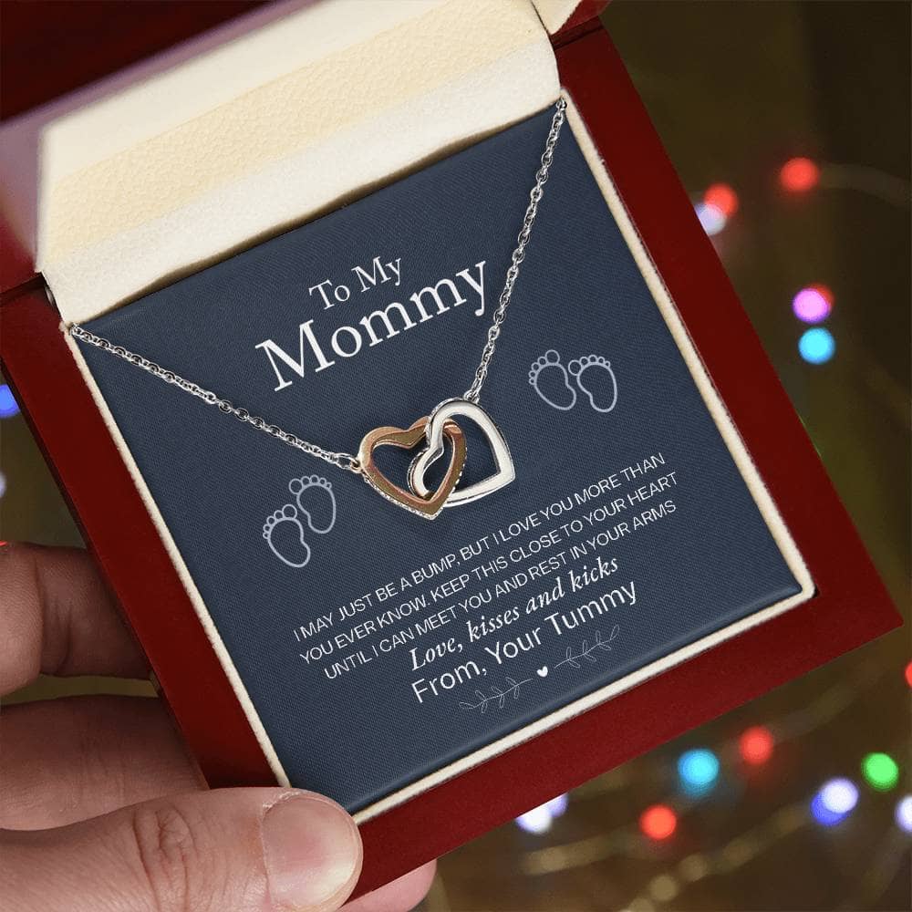 Alt text: "A hand holding the Interlocking Hearts Necklace, a symbol of infinite love between a mother and child, adorned with cubic zirconia crystals."