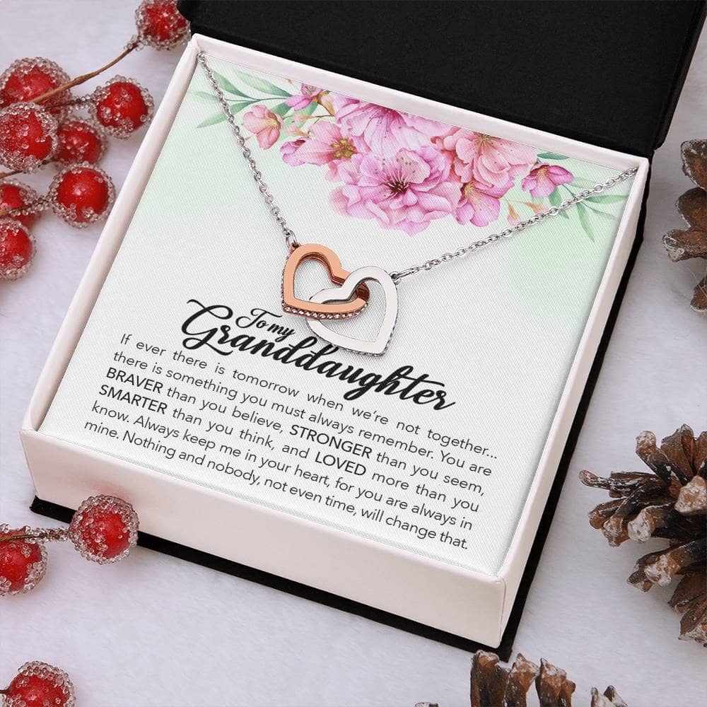 Interlocking Hearts Personalized Granddaughter Necklace: A necklace in a box with pine cones, berries, and a black surface.