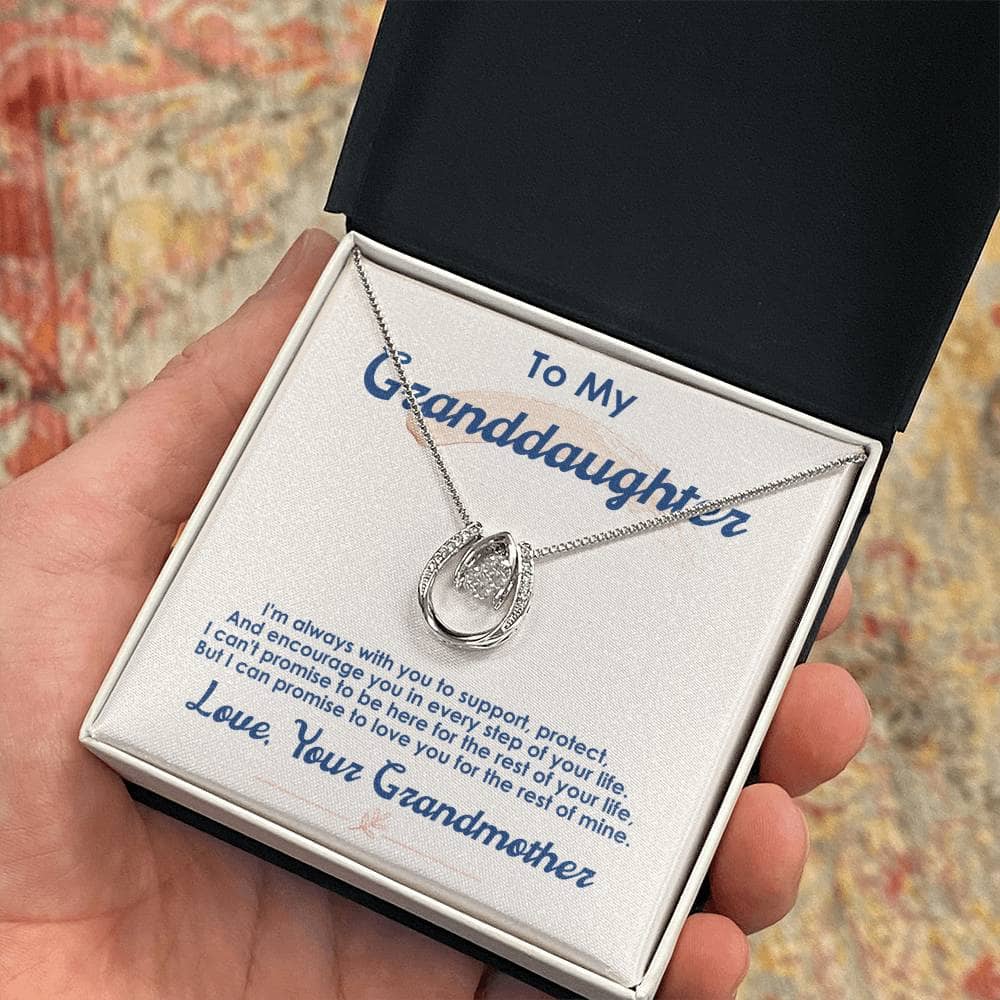 A hand holding a "Love for Eternity" Personalized Granddaughter Necklace in a box, showcasing a heart-shaped pendant with a cushion-cut cubic zirconia.