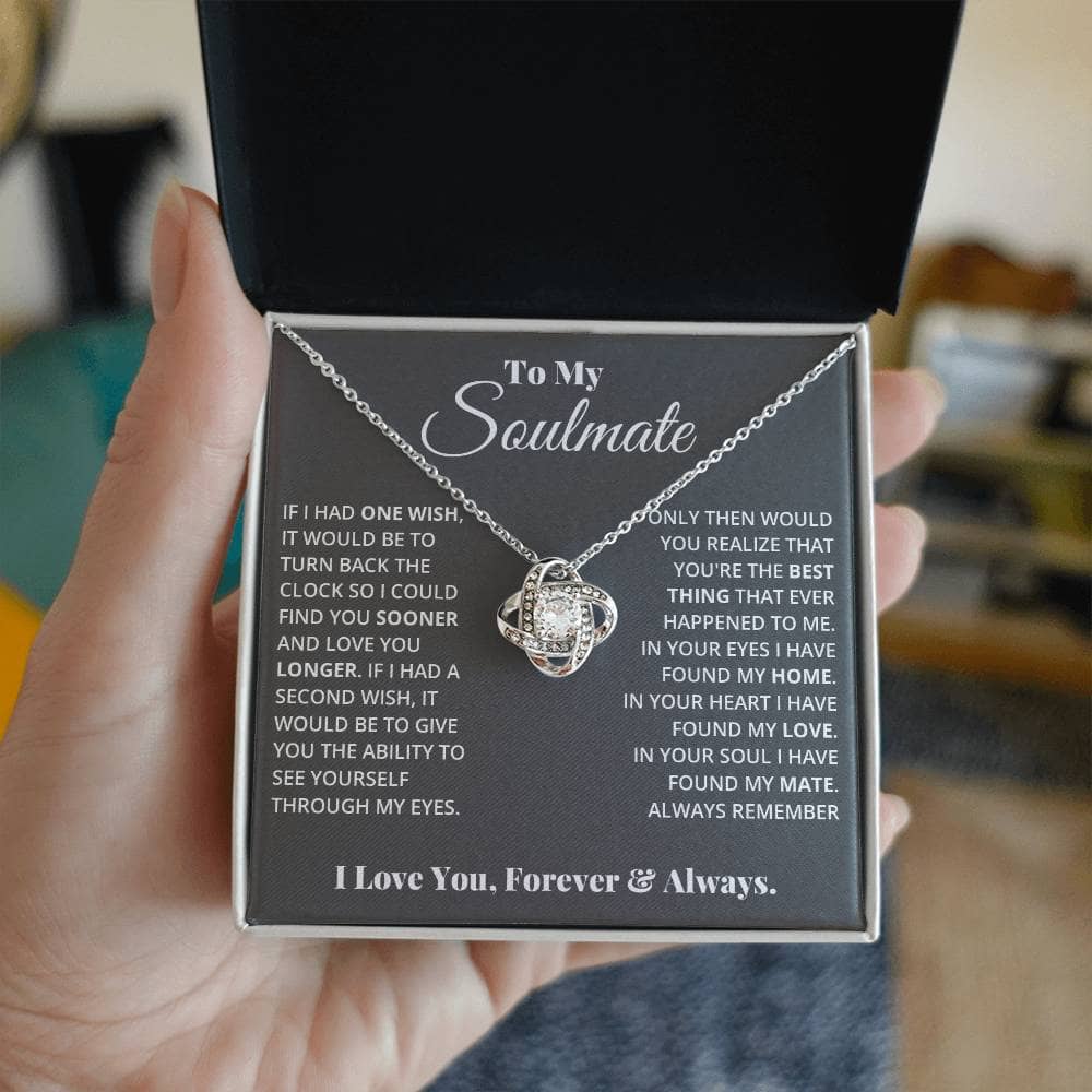 Alt text: "A hand holding the My Love Discovered in Your Heart - Soulmate Love Knot Necklace, a personalized necklace with a cubic zirconia pendant set in 14k white gold or 18k gold."