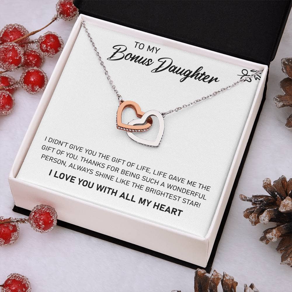 Alt text: "Personalized Daughter Necklace - A heart-shaped pendant in a box surrounded by pine cones and berries"
