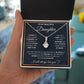 Alt text: "A hand holding a personalized daughter necklace with an elegant heart pendant in a box"