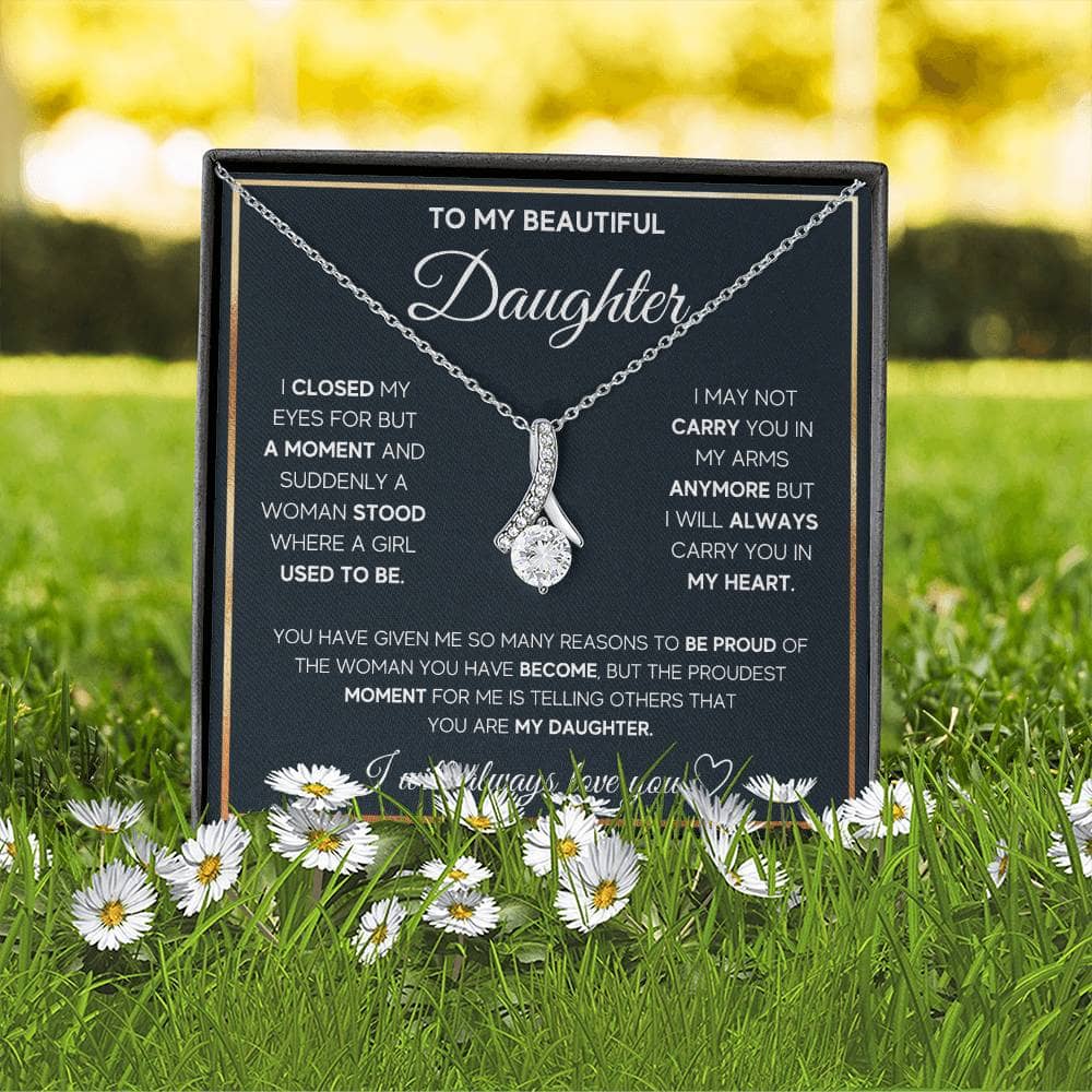 Alt text: "Personalized Daughter Necklace - Elegant heart pendant on a black box with flowers in the grass"