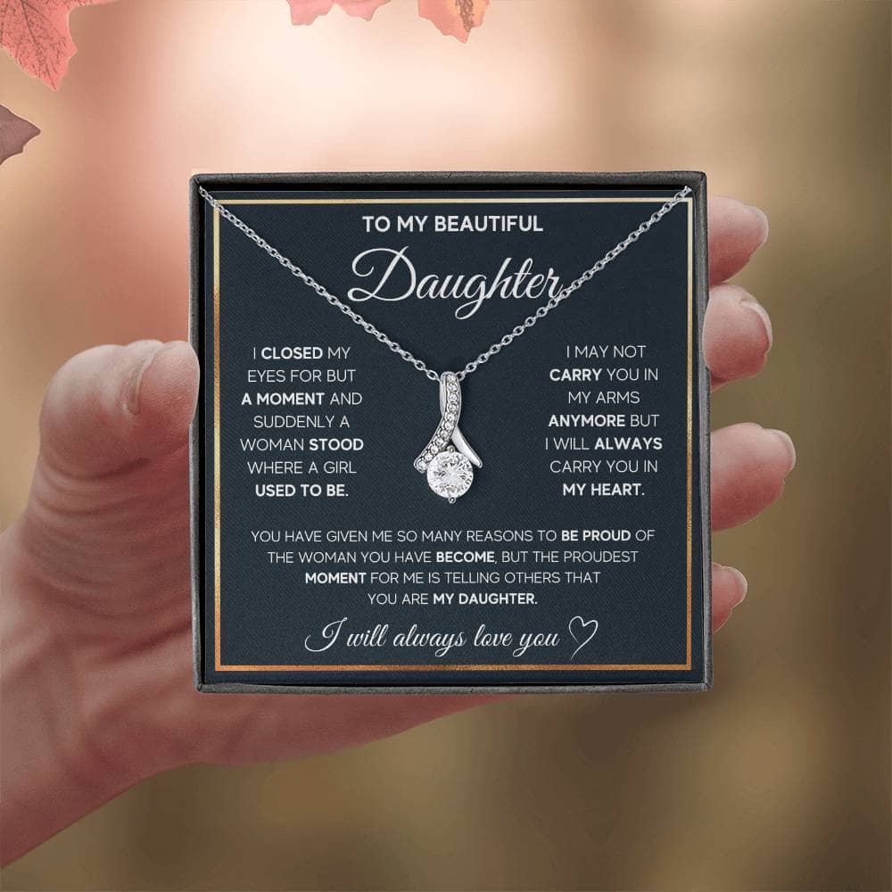 Alt text: "A hand holding a personalized daughter necklace with an elegant heart pendant"