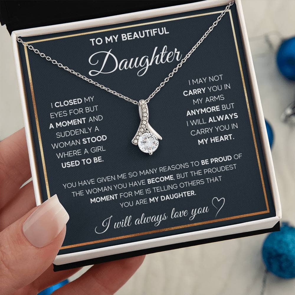 A hand holding a Personalized Daughter Necklace - Elegant Heart Pendant, symbolizing relentless parental love. Crafted with top-notch materials and adorned with cushion-cut cubic zirconia, this necklace is a flawless blend of grace and sophistication. Perfect for everyday wear or special events.