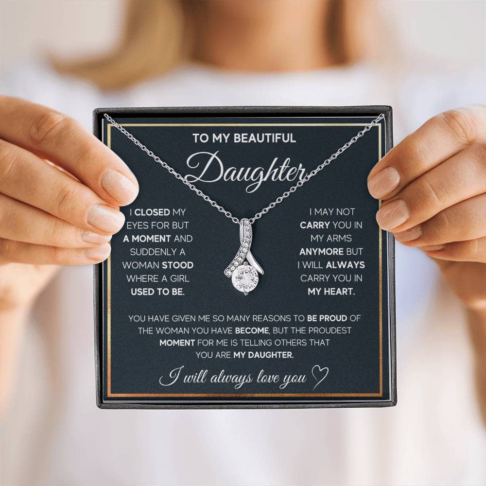 A person holding a personalized daughter necklace with an elegant heart pendant.