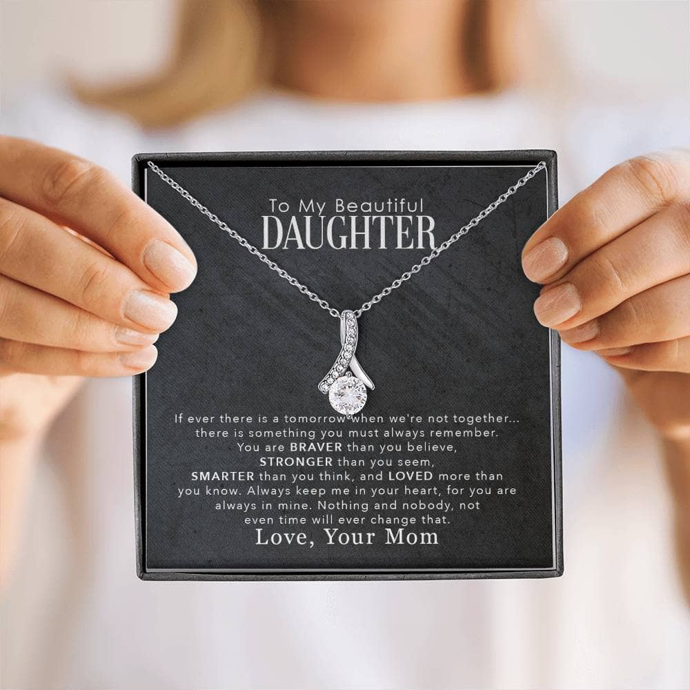 Alt text: "Person holding a personalized daughter necklace with heart-shaped pendant, symbolizing a deep familial bond"