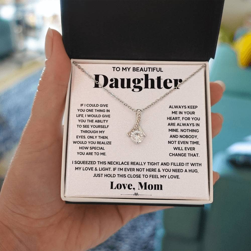 A hand holding a Personalized Daughter Necklace in a box, symbolizing the enduring bond between parents and daughters.