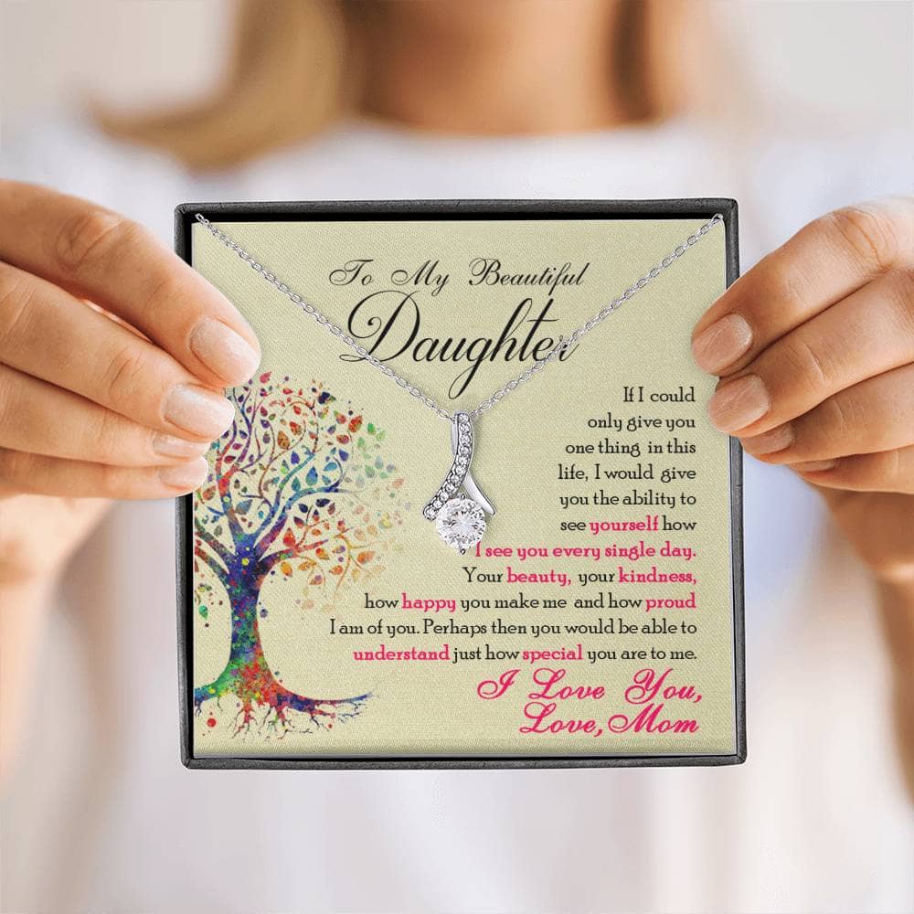 Alt text: "A hand holding a personalized daughter necklace with a heart-shaped pendant and cubic zirconia stone, symbolizing parental affection."