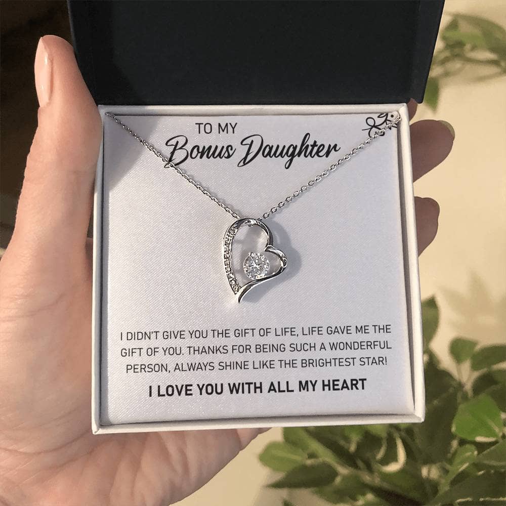 A hand holding a Personalized Daughter Necklace in a box, featuring a heart-shaped pendant with a diamond in the middle.