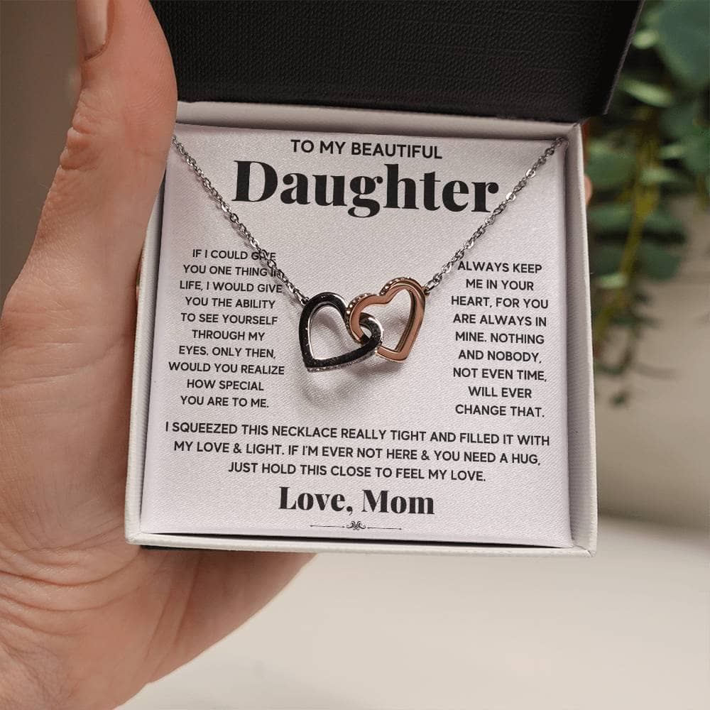 A hand holding a Personalized Daughter Necklace - Interlocking Hearts, symbolizing the eternal bond between parent and child.