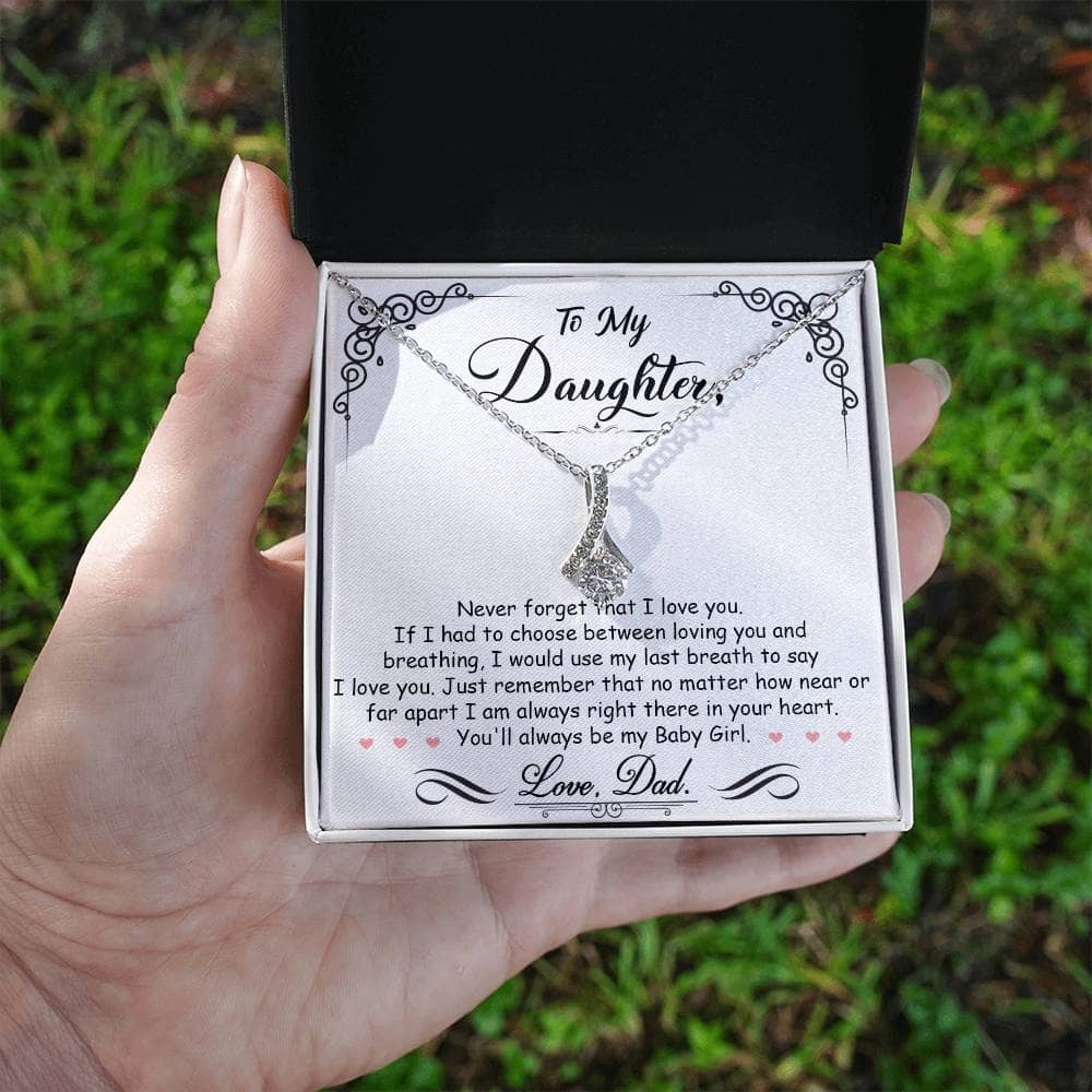 A hand holding a personalized Daughter Necklace in a box, adorned with a heart-shaped pendant and cushion-cut cubic zirconia.