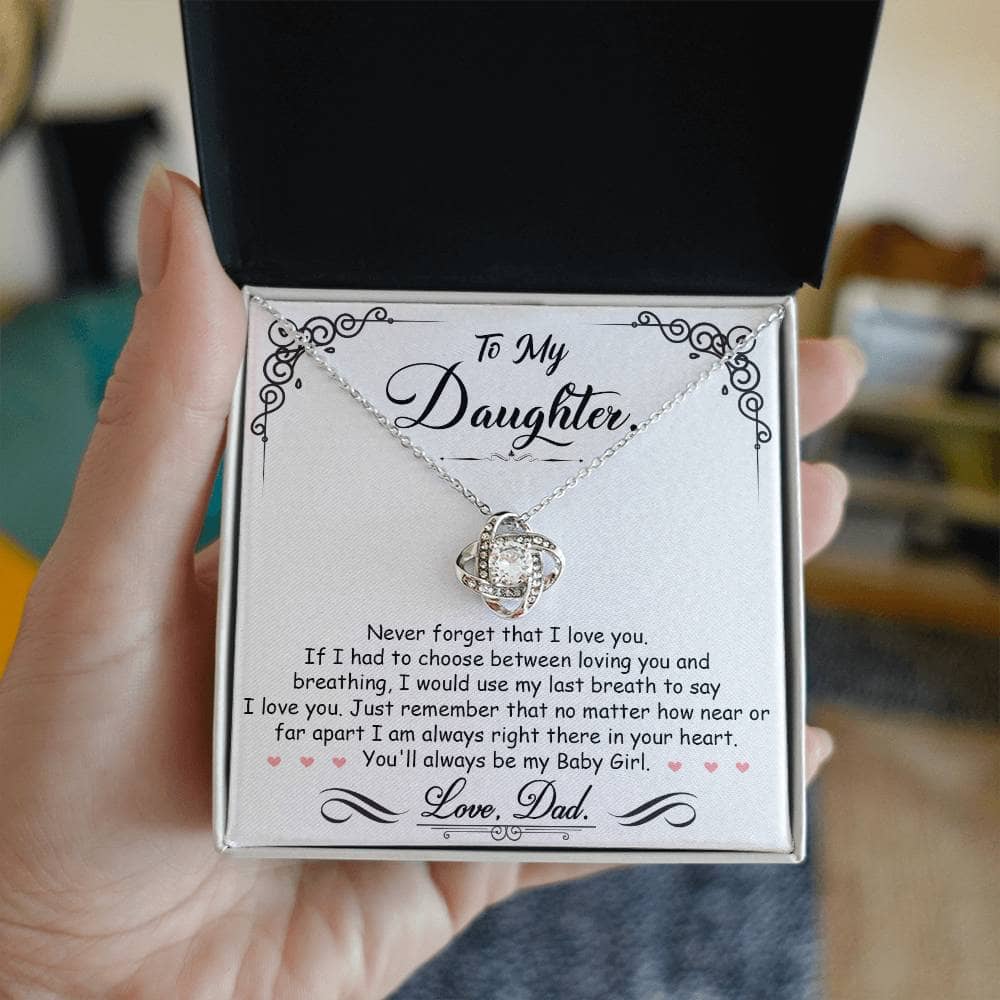 A hand holding a personalized Daughter Necklace in a box, featuring a glimmering cushion-cut cubic zirconia pendant symbolizing the bond between parents and daughters.