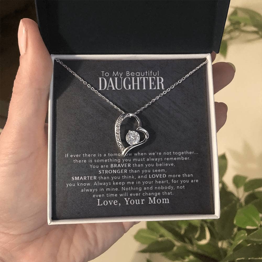 Alt text: "A hand holding a heart-shaped Personalized Daughter Necklace in a luxury box illuminated by LED lighting"