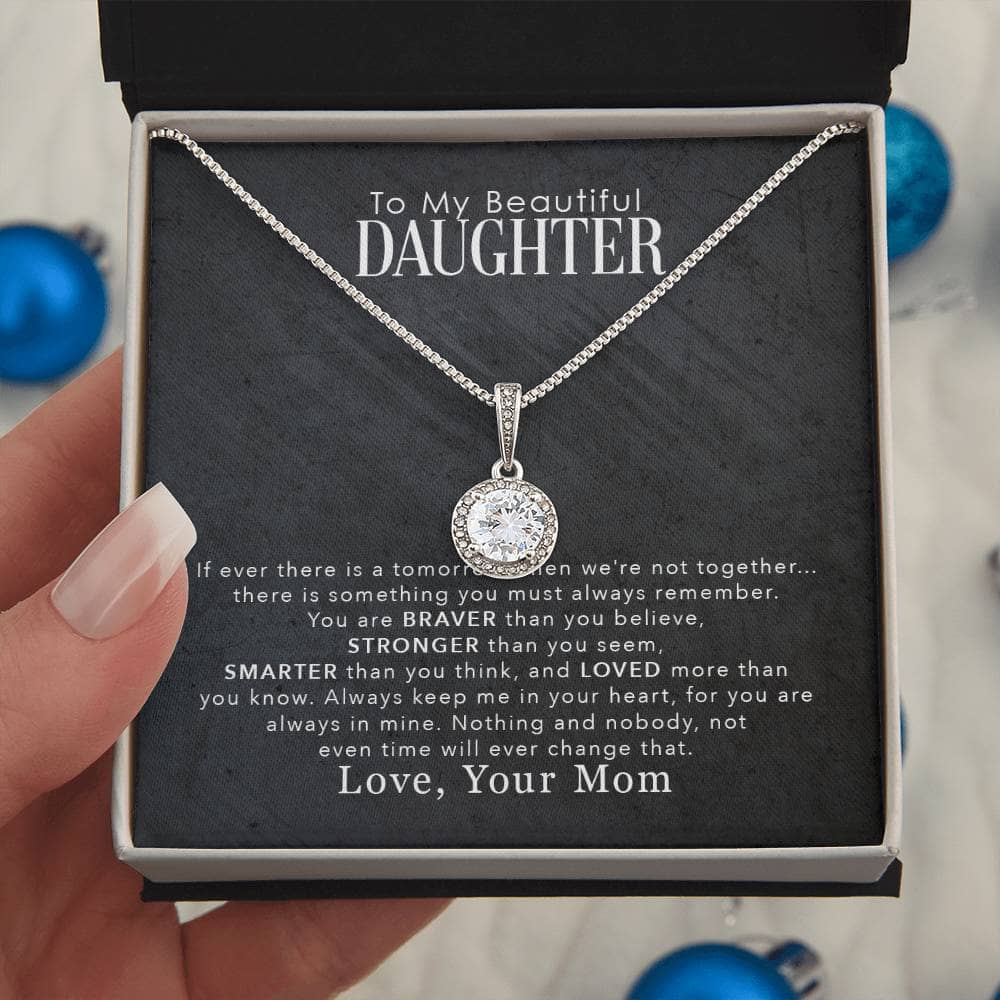 A hand holding a Personalized Daughter Necklace in a box, symbolizing love and strength.