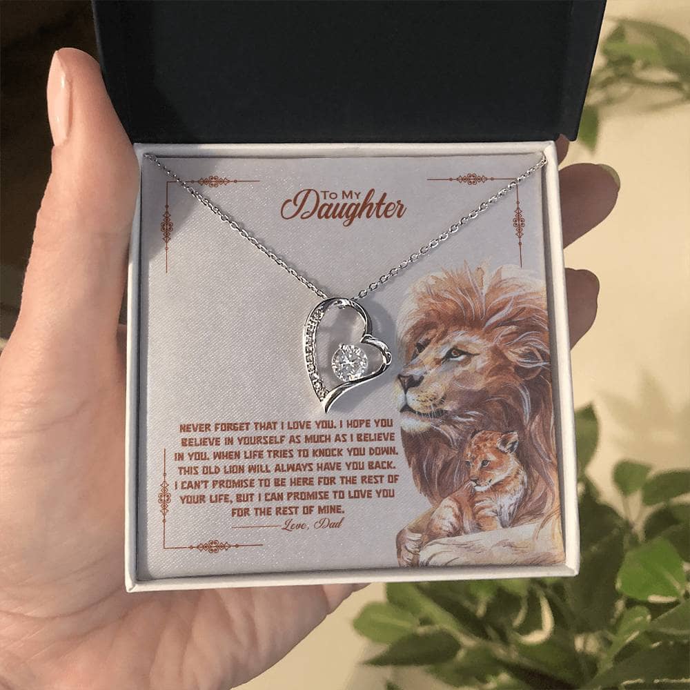 A hand holding a necklace in a box from the "To My Daughter" Necklace Collection, featuring a personalized daughter necklace crafted with cushion-cut cubic zirconia stones and an adjustable chain length. Packaged in a mahogany-style box with LED lighting for an unforgettable unboxing experience.