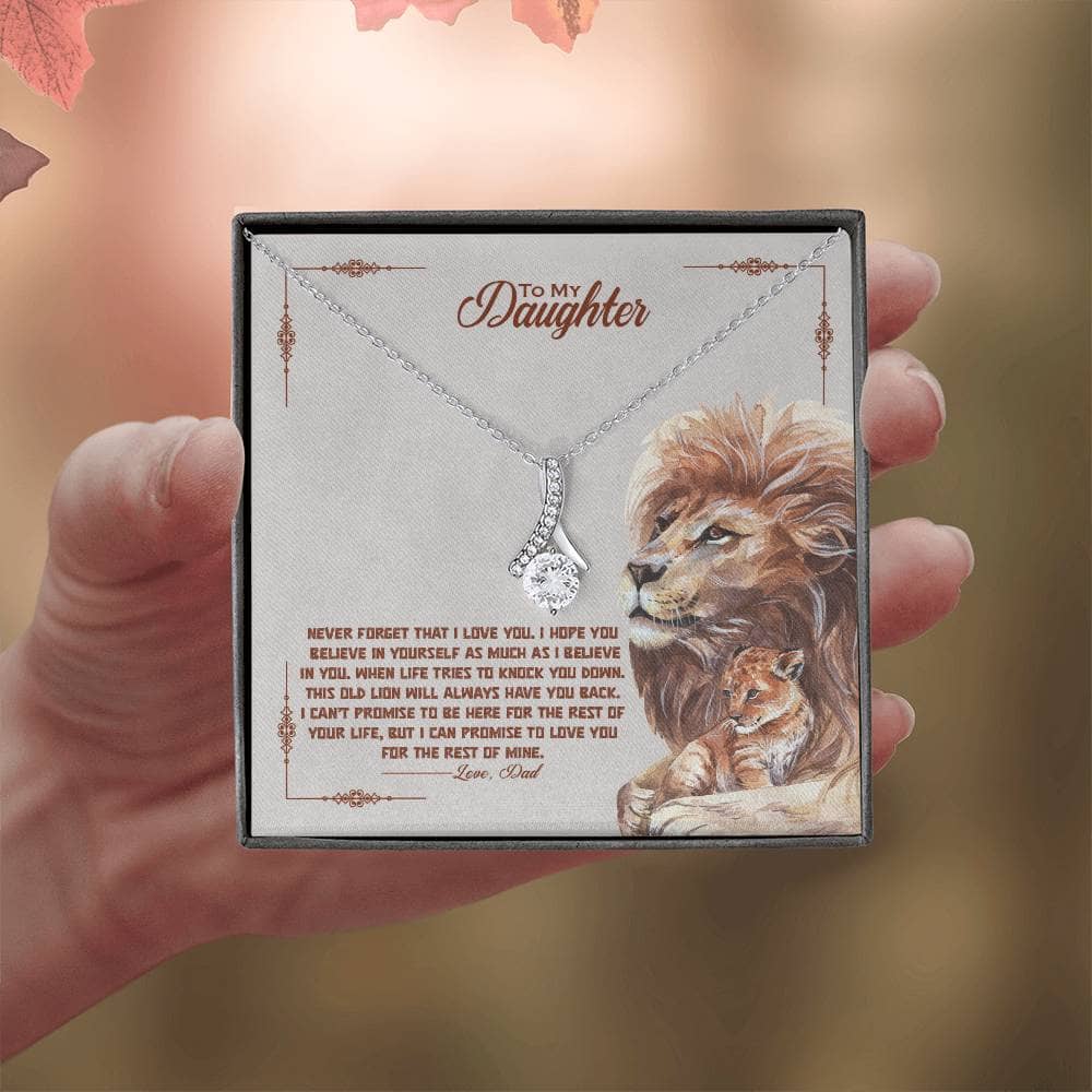 Alt text: "Hand holding a personalized daughter necklace with heart-shaped pendant and lion design"