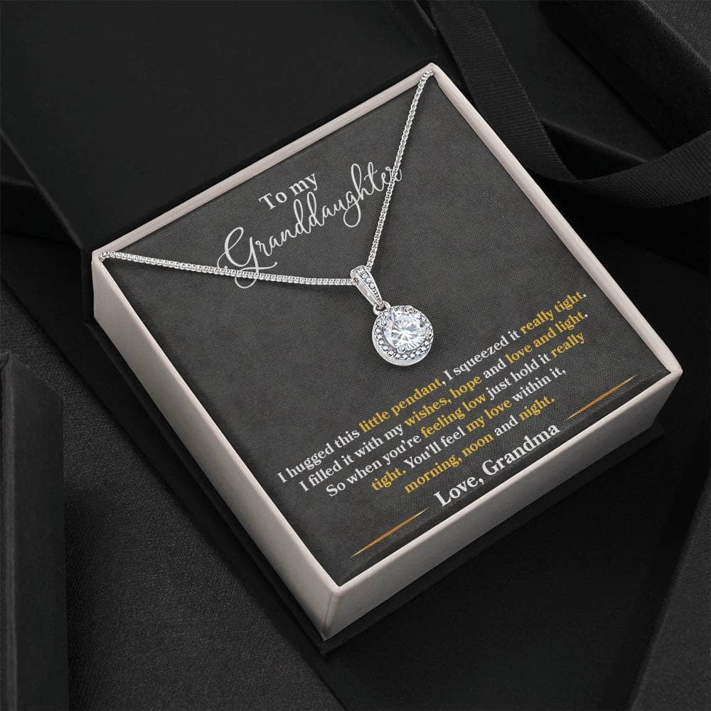 A close-up of the Personalized Granddaughter Heart Necklace, featuring a dazzling cushion-cut cubic zirconia crystal surrounded by accent CZ crystals. The pendant measures 0.6" in height and 0.5" in width. Adjustable box chain length of 16" - 18". Lovingly packaged in a soft touch box for easy gifting.