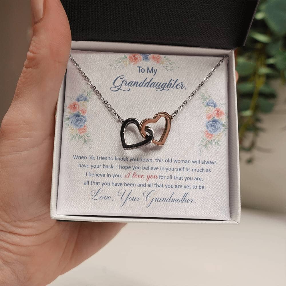 Alt text: "A hand holding a Personalized Granddaughter Love Pendant necklace with two hearts, symbolizing the unyielding bond between a granddaughter and her grandparents."