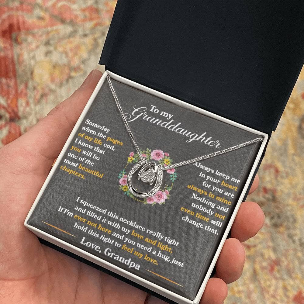 Alt text: "A hand holding a personalized granddaughter necklace in a box"
