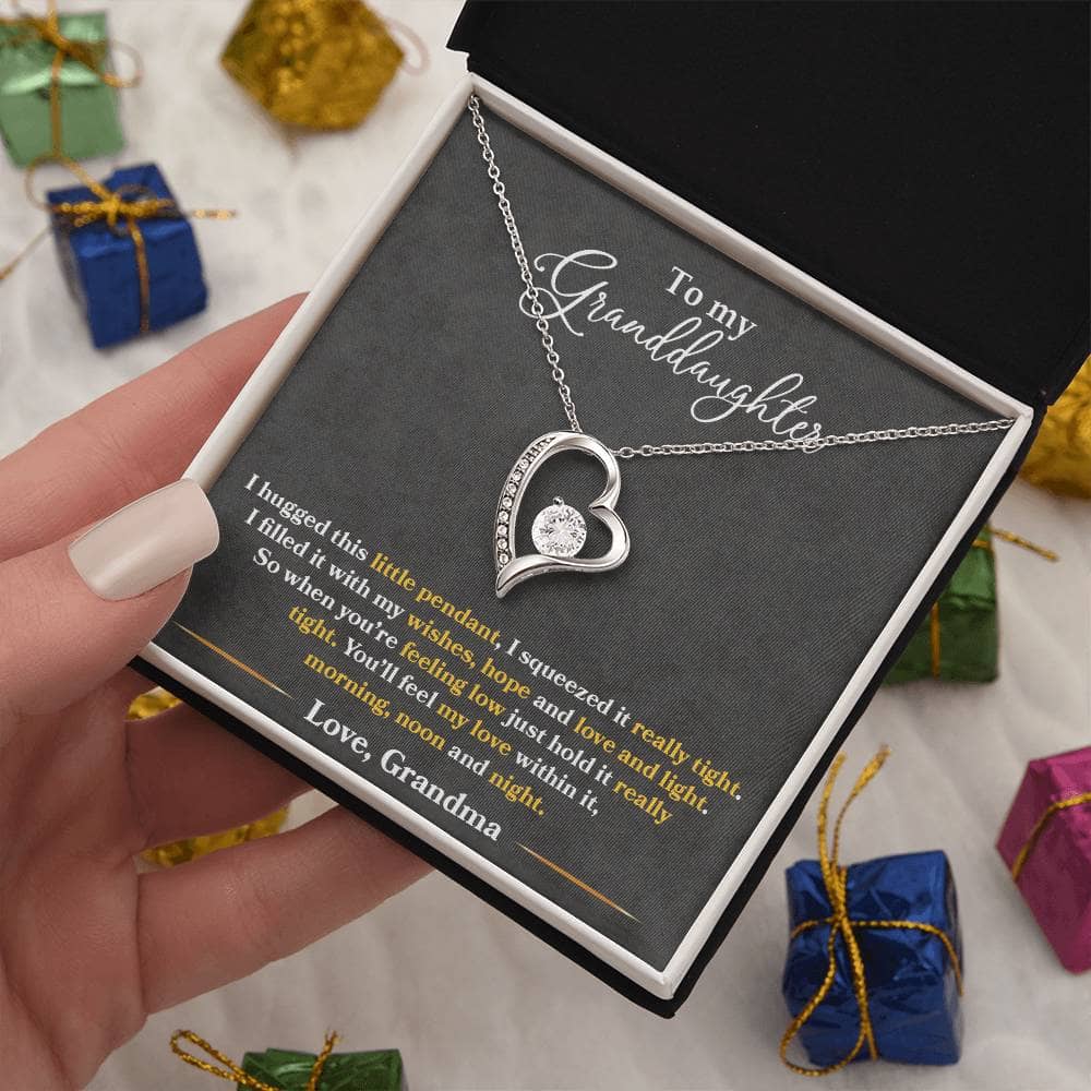 Alt text: "A hand holding a Personalized Granddaughter Necklace - Forever Love Token in a box"