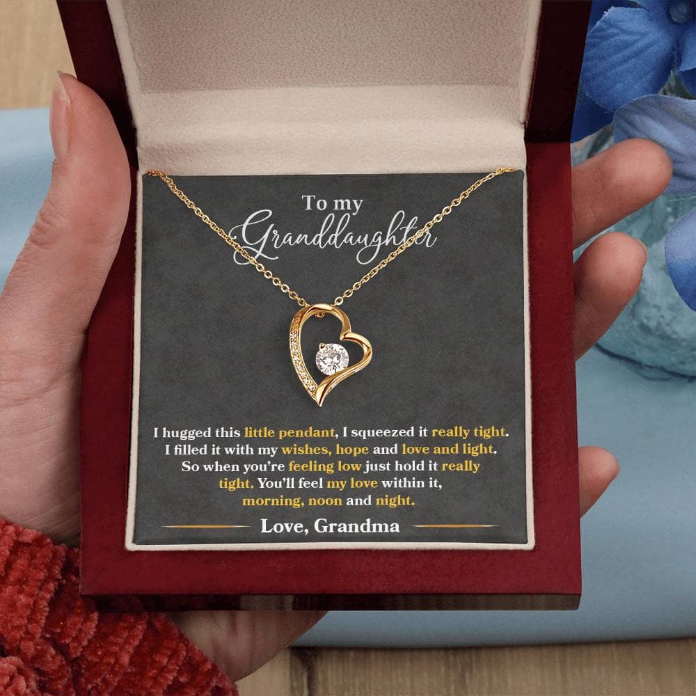 Alt text: "A hand holding a heart-shaped pendant necklace in a box, symbolizing the everlasting love between grandmothers and granddaughters."