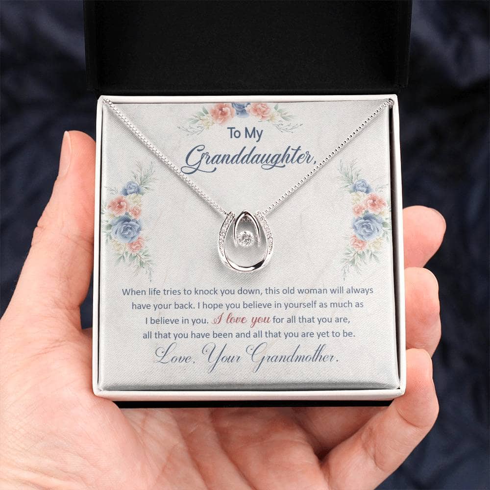 A hand holding a Personalized Granddaughter Necklace with a heart pendant.