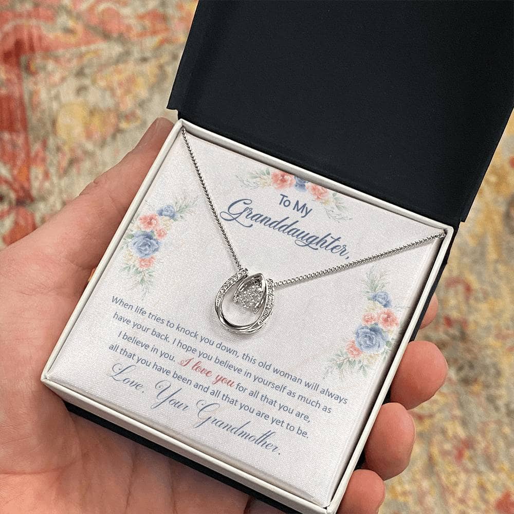 A hand holding a Personalized Granddaughter Necklace with a heart pendant in a box.