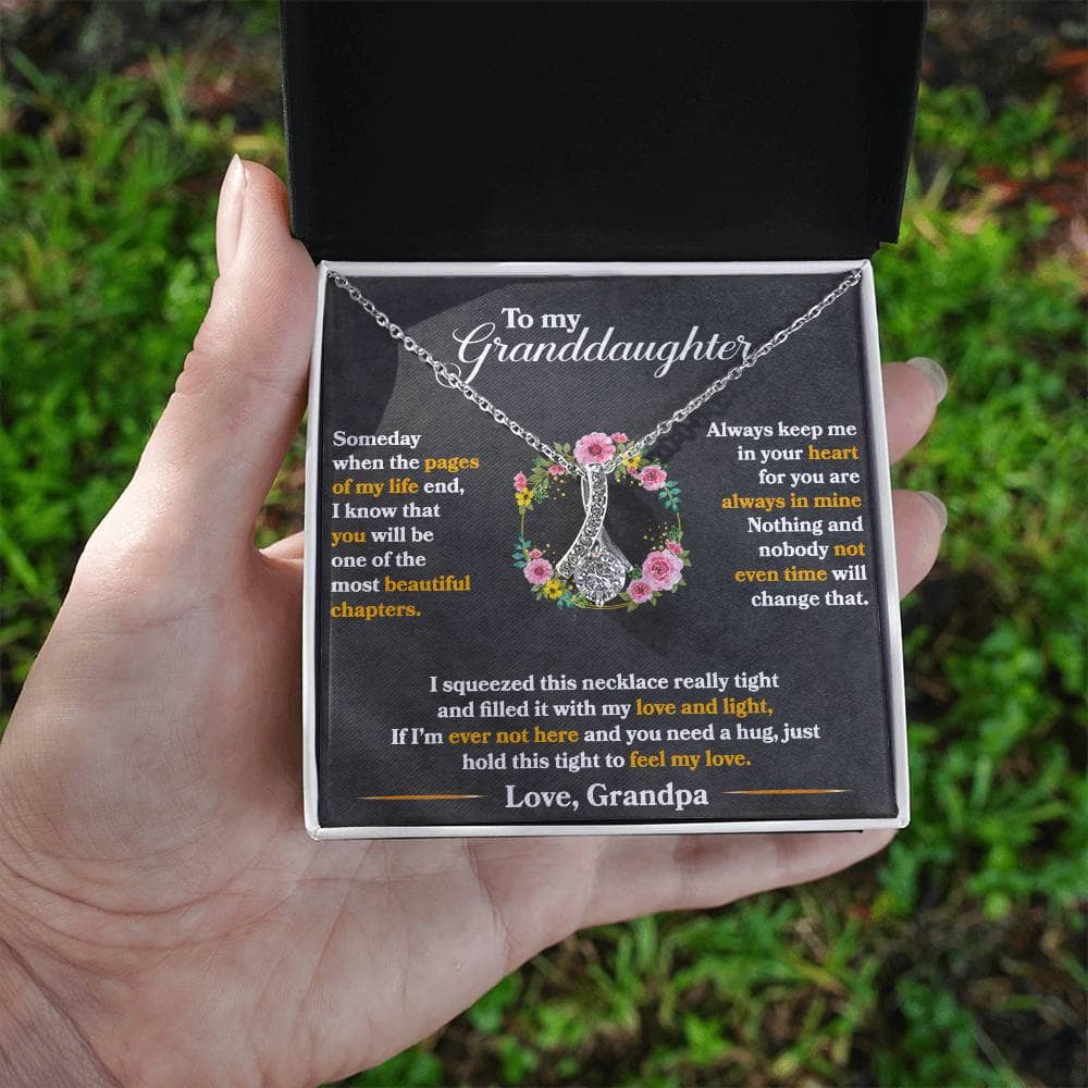 Alt text: "A hand holding a Personalized Granddaughter's Embrace Necklace in an elegant mahogany-style box with LED lighting."