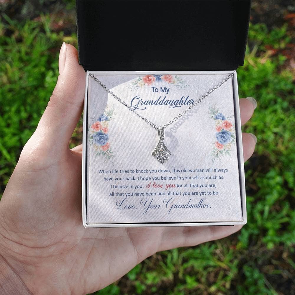 A hand holding a Personalized Keepsake Necklace for Granddaughter in a box, symbolizing the enduring bond between generations.